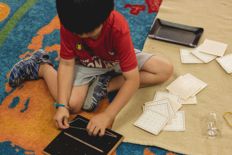 Kindergarten boy working with Montessori letter materials on a classroom rug at Country Montessori School in Poway