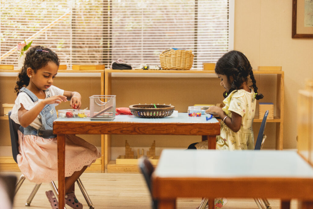 Two young girls working with Montessori materials in an Early Childhood classroom at Country Montessori School in Poway