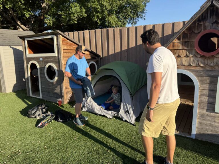 A camper sets up his tent with parents during the Adventure Camp overnight campout on the CMS campus
