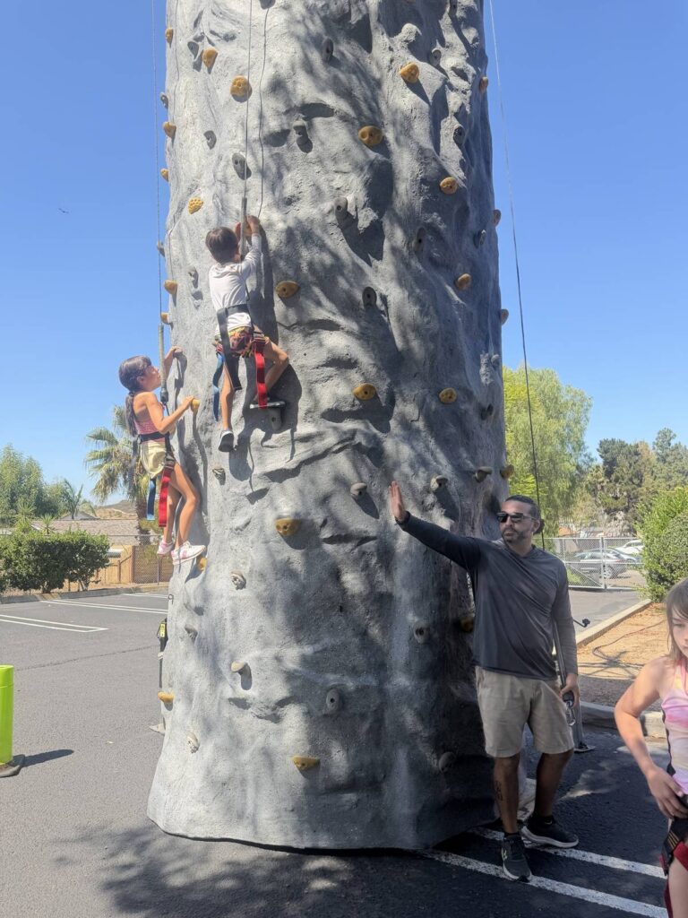 Campers climbing a rock-climbing wall at Adventure Camp at Country Montessori School