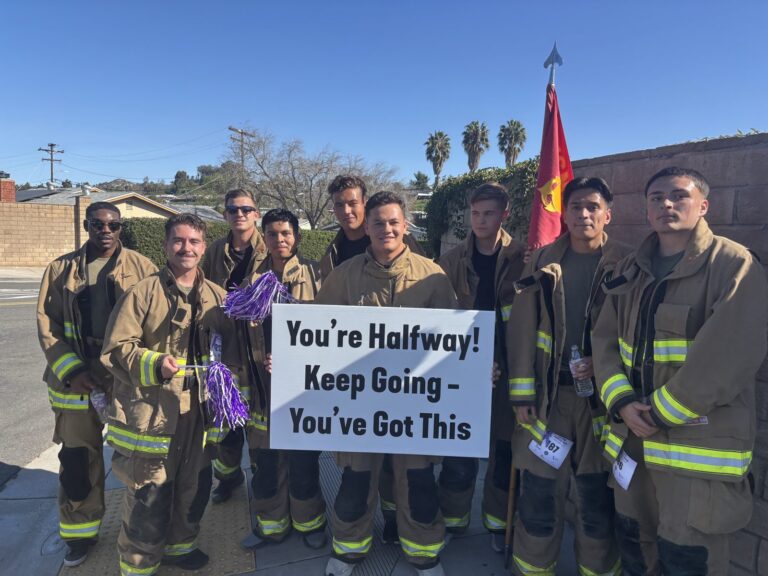 Firefighters in turnout gear holding a "You're Halfway! Keep Going" sign on the Firefighters for Hope route