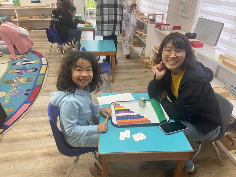 Student showing her mom a Montessori lesson with colored bead materials during Mothers' Night